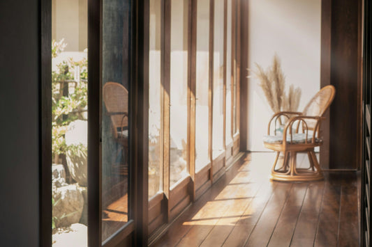 sunlit interior hallway with wooden floors and a rattan chair, soft natural light creating a calm, quiet atmosphere