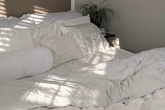 soft natural light over a white bed with textured pillows, creating a calm and restful home atmosphere