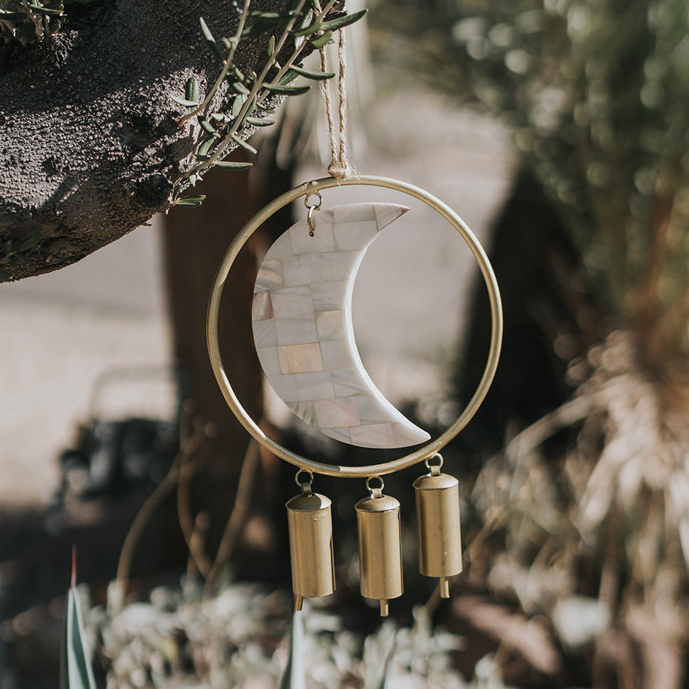 crescent moon wind chime hanging outdoors with soft natural light and calming garden setting