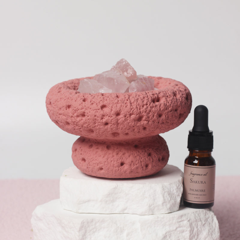 Pink Moon Vessel diffuser filled with crystals displayed on natural wood and moss with Sakura fragrance oil