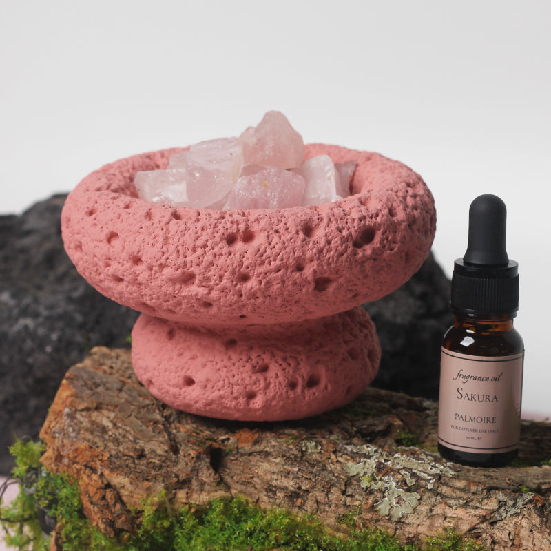 Pink Moon Vessel diffuser filled with crystals displayed on natural wood and moss with Sakura fragrance oil